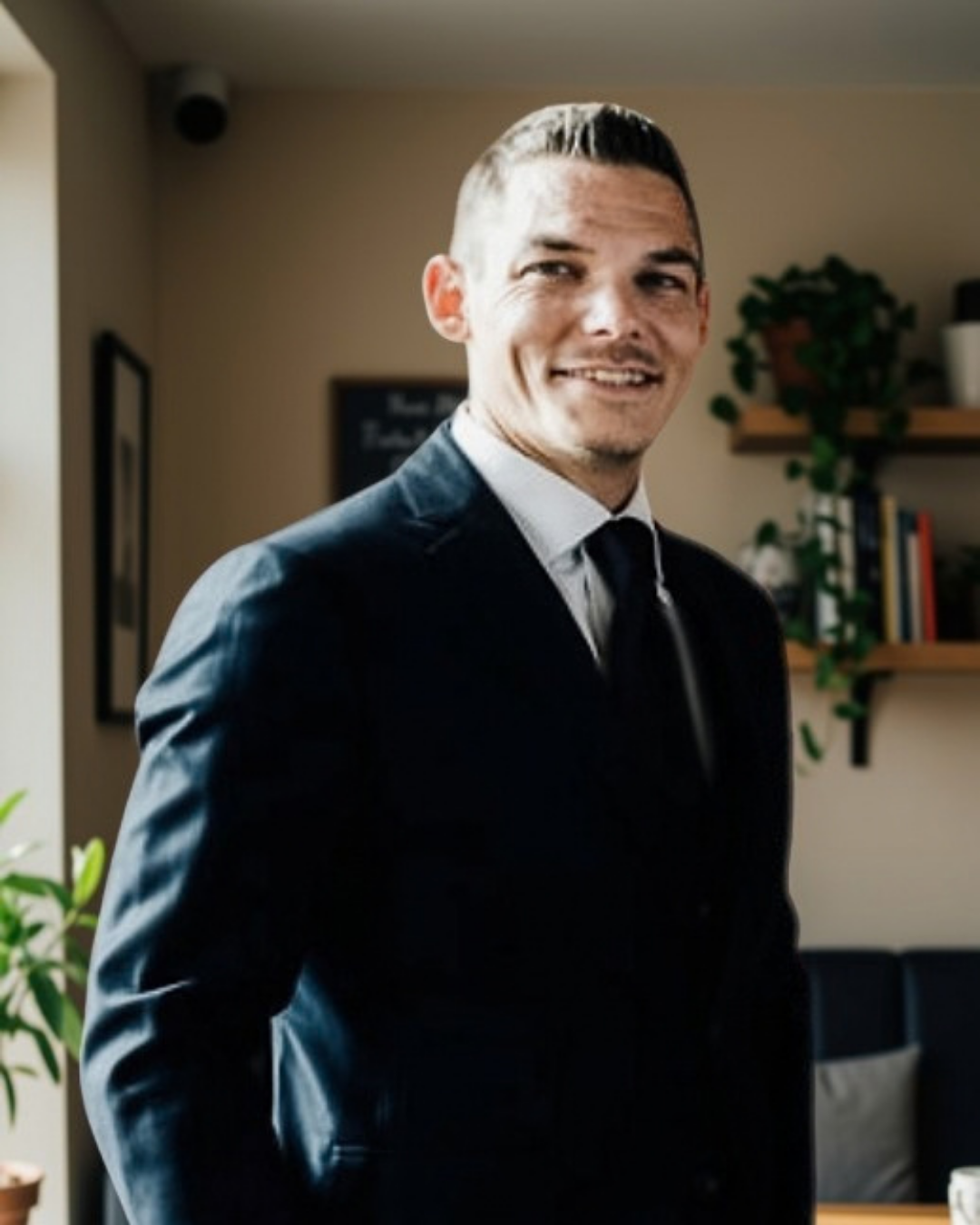 Jordan in a navy suit, smiling in a cafe